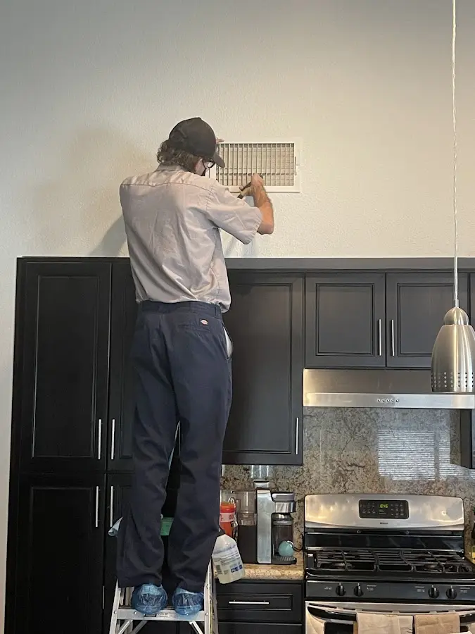Technician inspecting an air vent during HVAC service in Fair Oaks
